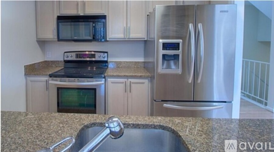 A kitchen with a black microwave above the stove and a stainless steel refrigerator.