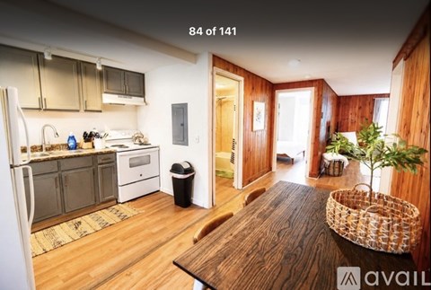 A kitchen with wooden floors and a refrigerator on the left.
