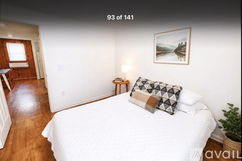 A bedroom with a bed, a lamp, and a painting on the wall.