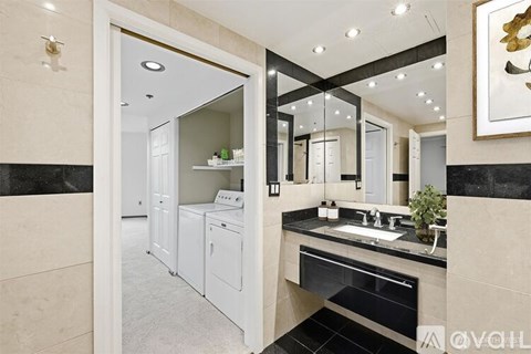 A modern bathroom with a large mirror and a washing machine in the laundry area.