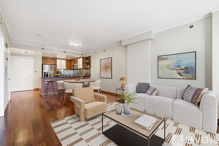 A living room with a grey couch, a coffee table, and a painting on the wall.