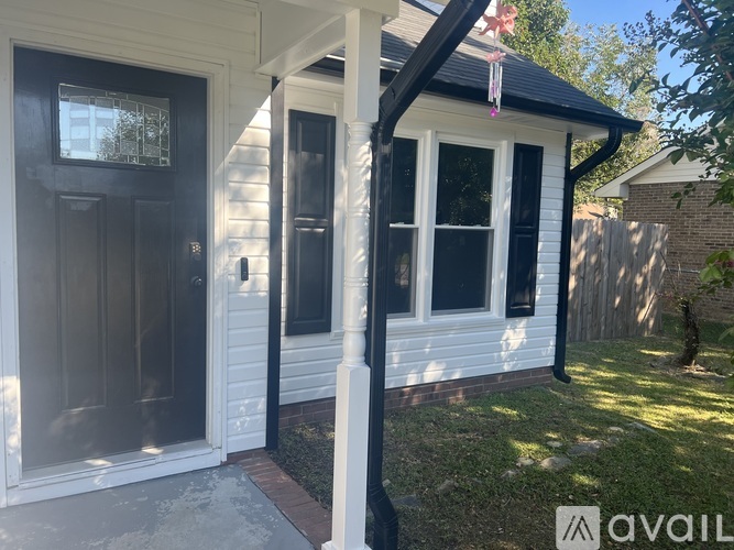 A white house with a black door and a black and white porch.