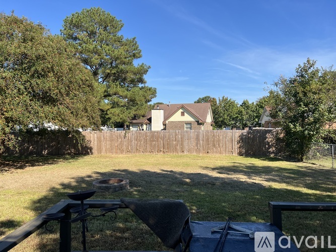 A backyard with a wooden fence and a house in the background.