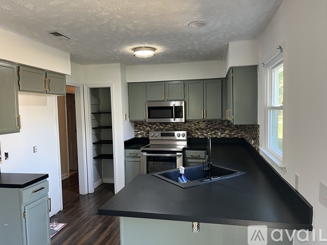 A kitchen with a black countertop and green cabinets.