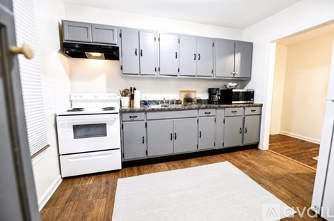 A kitchen with white appliances and grey cabinets.