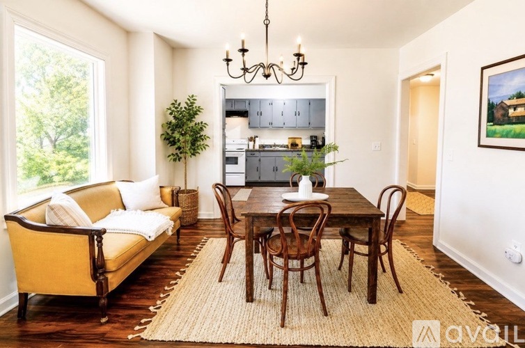 A living room with a yellow couch, a wooden table, and a chandelier.