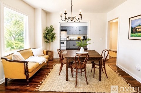 A living room with a yellow couch, a wooden table, and a chandelier.
