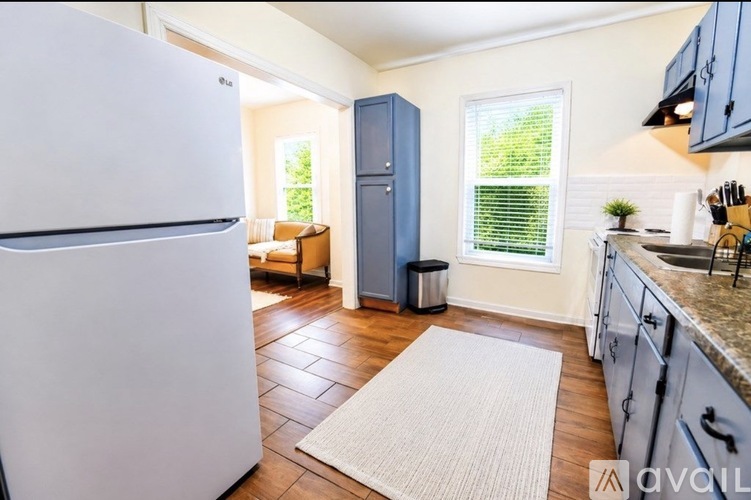 A white refrigerator is in a kitchen with a white rug on the floor.