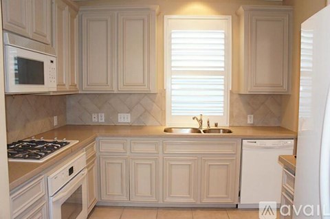 A kitchen with white cabinets and appliances.