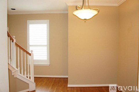A room with a wooden floor, a staircase, and a chandelier.