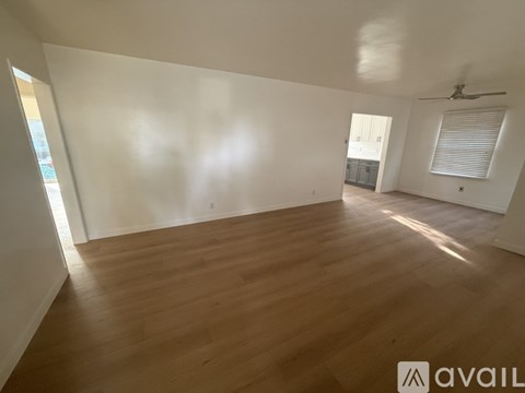 A spacious room with wooden flooring and white walls.