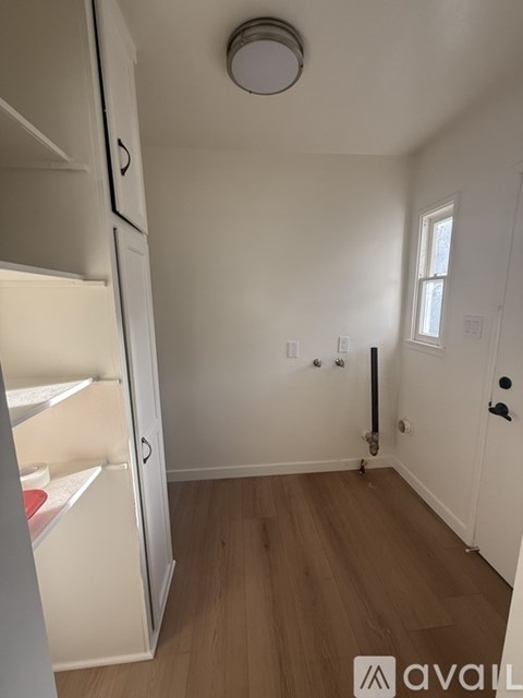 A small, empty room with a white door and a white fridge.