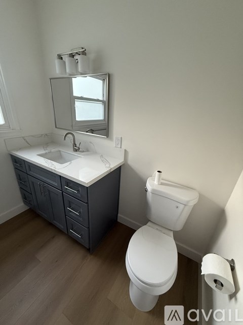 A bathroom with a toilet, sink, and mirror.