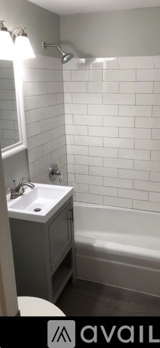 A bathroom with a white tiled wall and a white sink.
