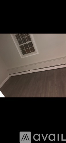 A room with a ceiling vent and wooden flooring.