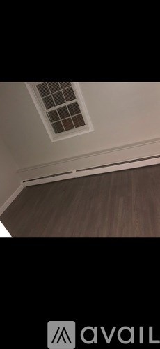 A room with a ceiling vent and wooden flooring.