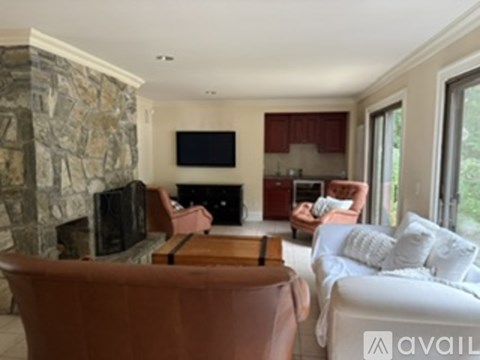 A living room with a stone fireplace and a flat screen TV mounted on the wall.