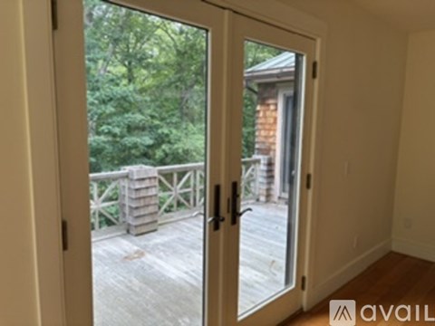A balcony with a railing and a view of a house and trees.