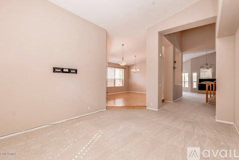 A spacious room with a sign on the wall and a hallway leading to another room.