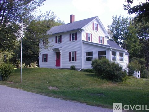 A white house with red shutters and a red door.