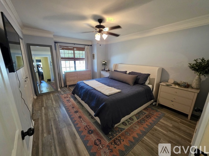 A bedroom with a bed, dresser, and a ceiling fan.