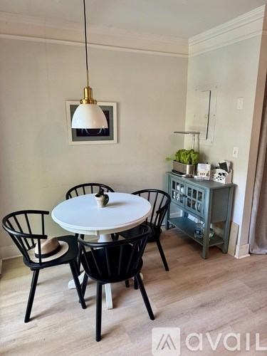 A dining room with a white table and black chairs.