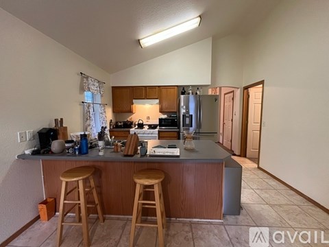 A kitchen with wooden cabinets and a bar area with stools.