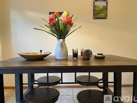 A table with a vase of flowers, a bowl, and some decorative items on it.