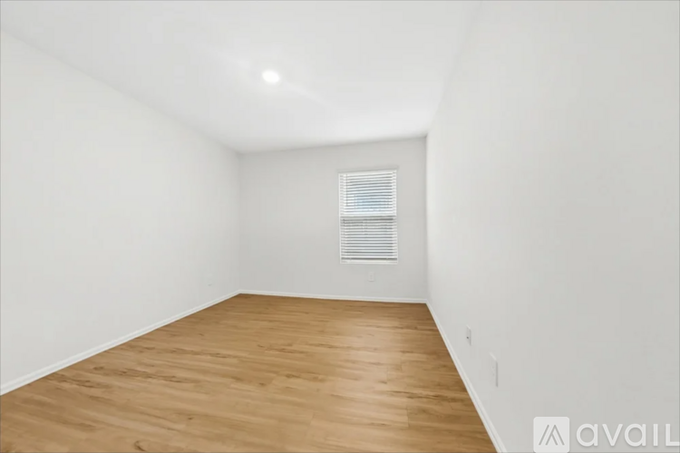 A room with wooden flooring and a window with blinds.