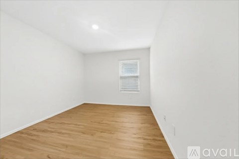 A room with wooden flooring and a window with blinds.