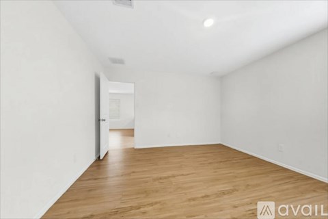 A room with wooden flooring and white walls.