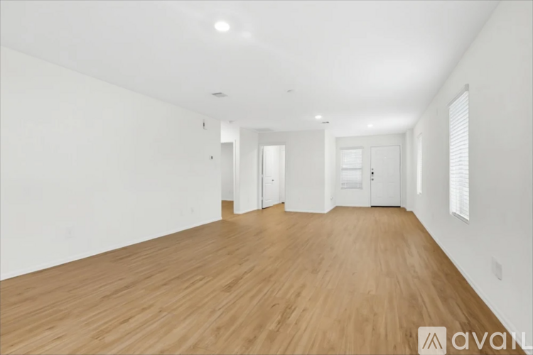 A spacious room with wooden flooring and white walls.