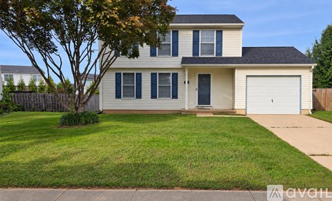 A two-story house with a garage and a tree in front.