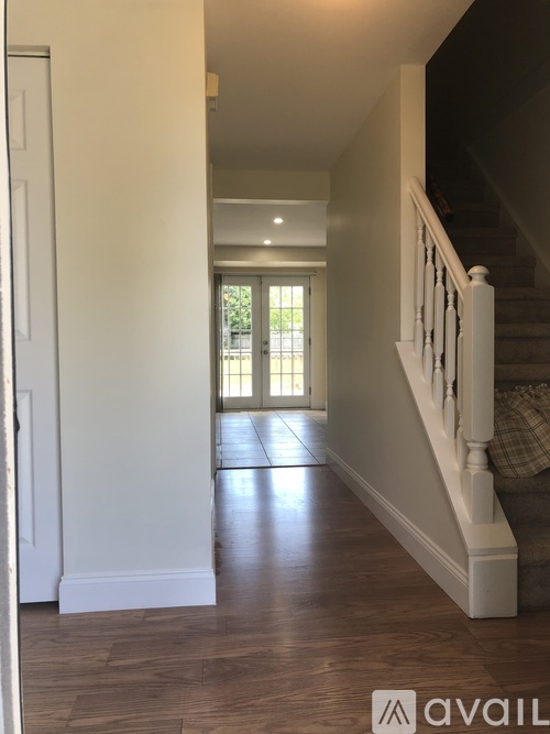 A hallway with a staircase and a door leading to a balcony.