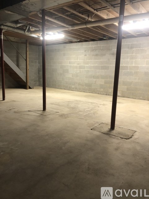 A spacious basement with concrete walls and a staircase in the background.