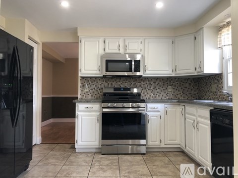 A kitchen with white cabinets and a black refrigerator.