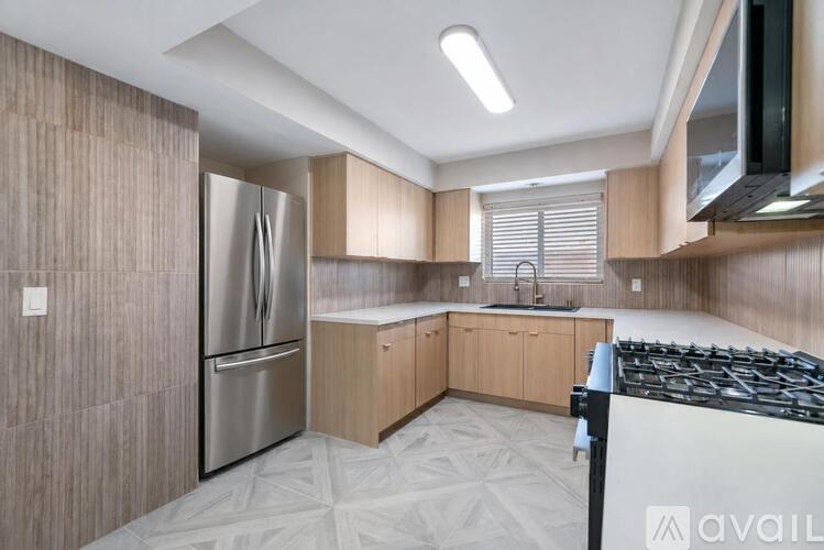 A kitchen with a stainless steel refrigerator and a black stove top.