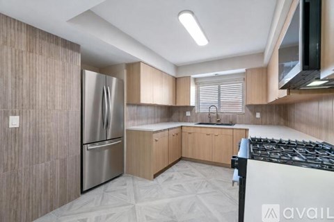 A kitchen with a stainless steel refrigerator and a black stove top.