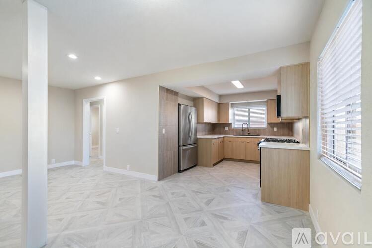 A spacious kitchen with a patterned floor and a refrigerator.