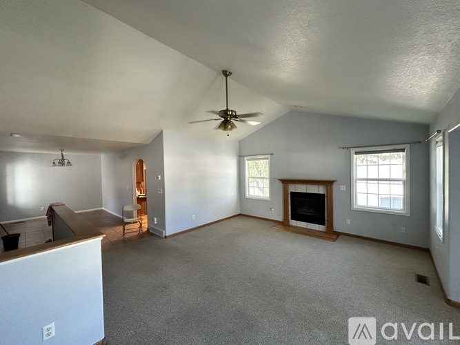 A spacious living room with a fireplace and a ceiling fan.