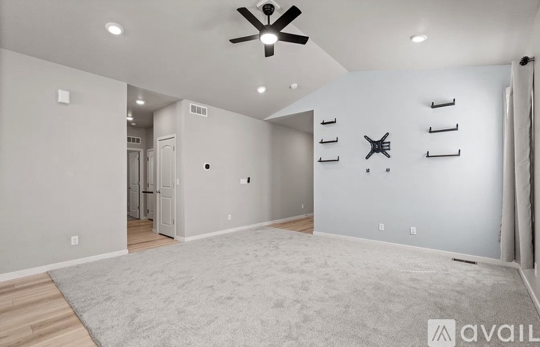A spacious room with a ceiling fan and a rug on the floor.