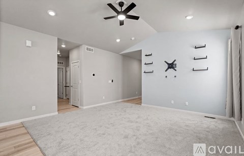A spacious room with a ceiling fan and a rug on the floor.