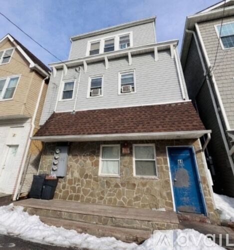 A house with a blue door is in front of a house with a brown roof.