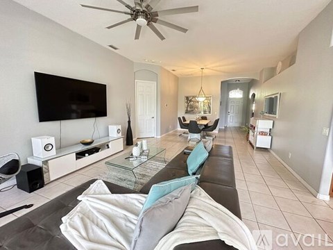 A living room with a television, a couch, and a ceiling fan.