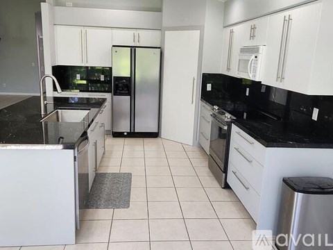 A kitchen with white cabinets and black countertops.