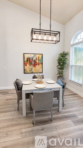 A dining room with a table set for two and a painting on the wall.