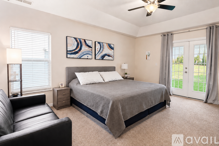 A bedroom with a bed, a couch, and a ceiling fan.