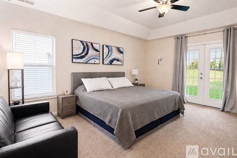 A bedroom with a bed, a couch, and a ceiling fan.