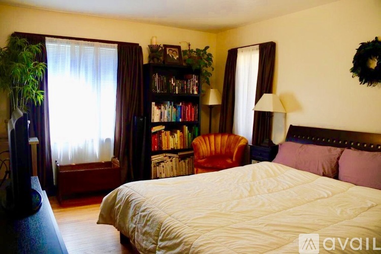 A bedroom with a large bed, a bookshelf, and a window with curtains.