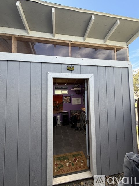 A grey building with a window showing a room inside.